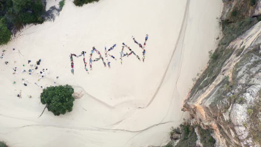 Litter left on a beach is used to spell on makay from viewed from a cliff above