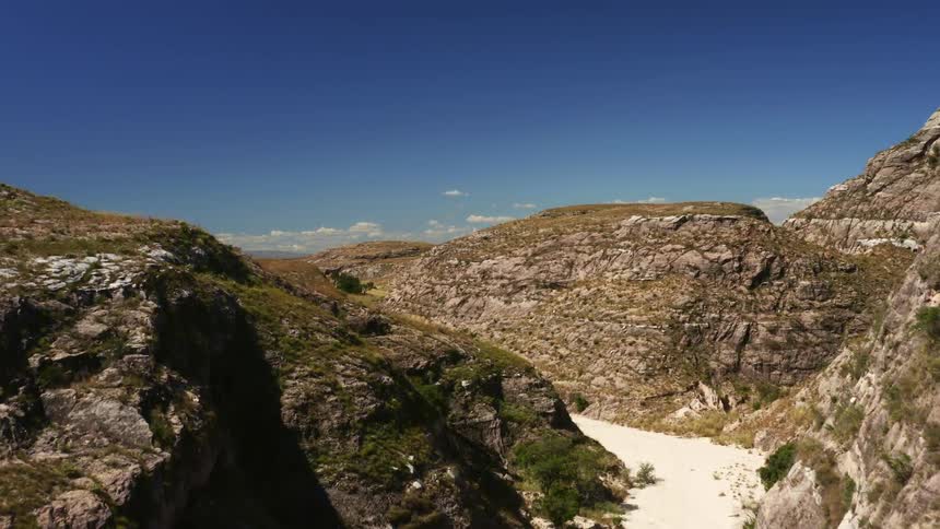 Narrow sandy strip winds among mountains under slightly cloudy blue sky