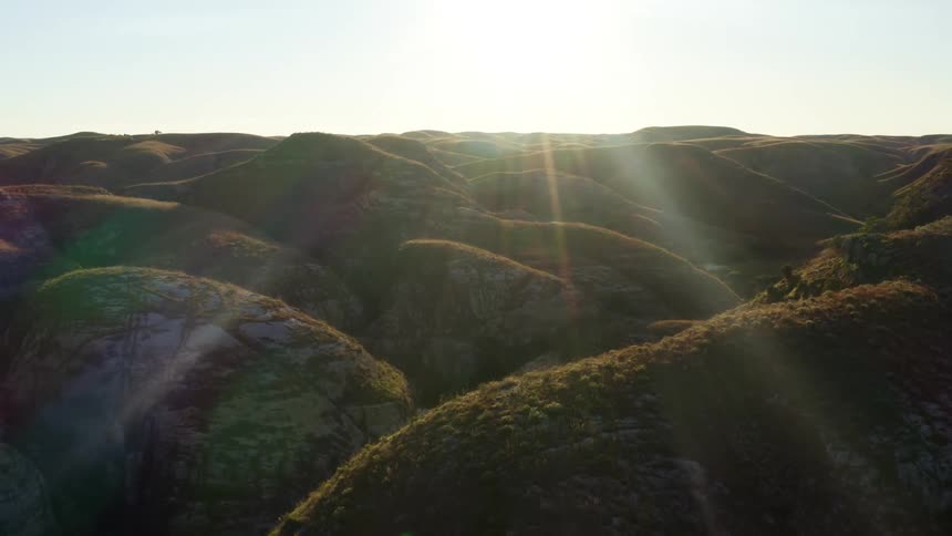 An aerial view of a landscape with hills is displayed