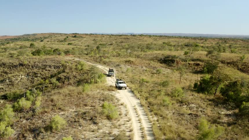 Aerial view of all terrain vehicles driving on a drit road through a plain