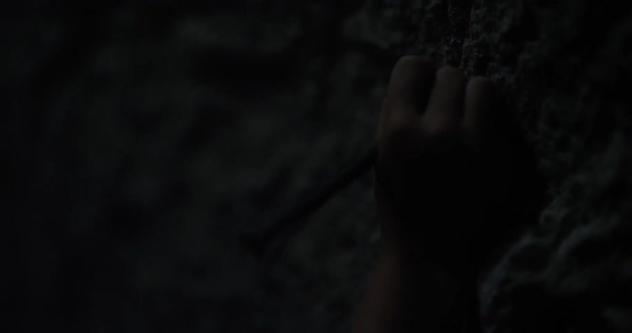 A person uses a tool to make marks on a rock