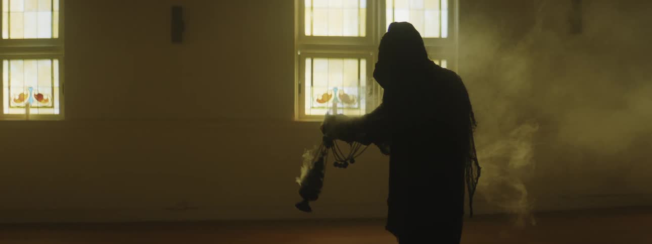 Monk in a robe fills a church with incense smoke