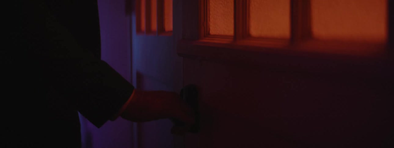 A person is walking into a house at night