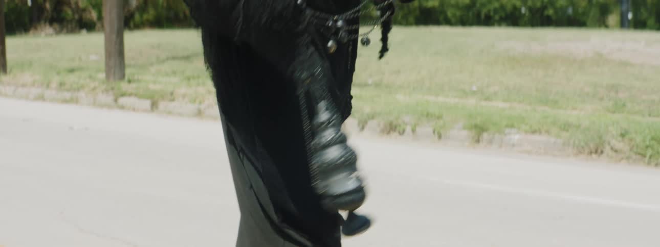 A person walking down a street swinginga heavy metal object on chains