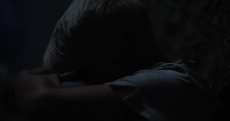 A young boy in distress sitting in a dark cave