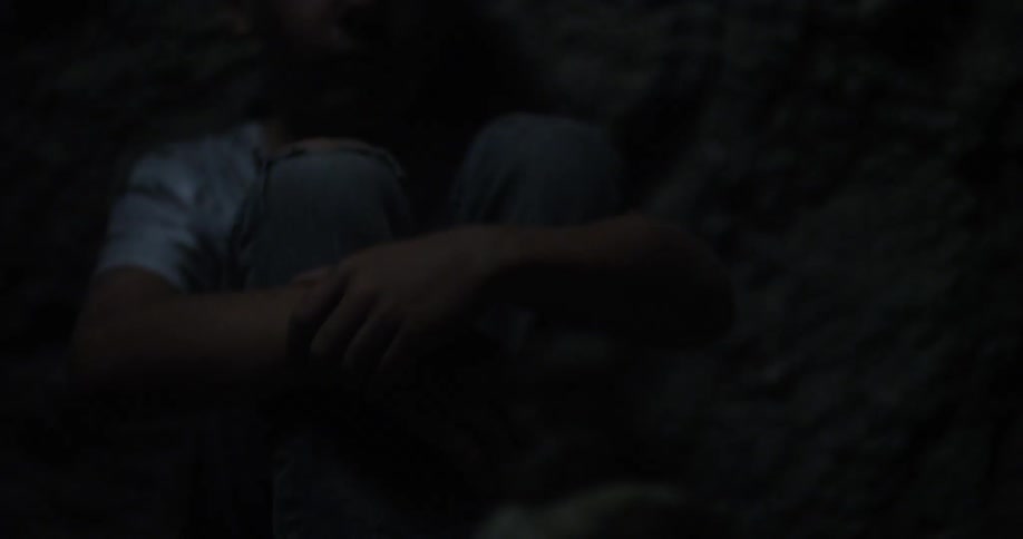 A boy is stacking rocks in a dark cave
