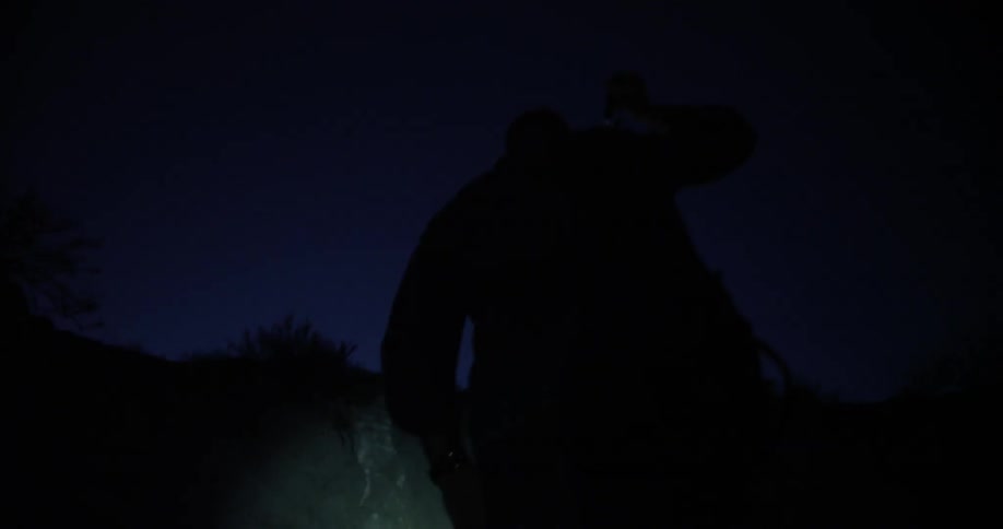 A man leaves a vehicle and shines a flashlight uphill as he walks
