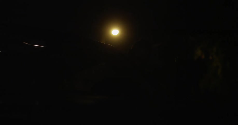 Man gets into a parked car on a dark night