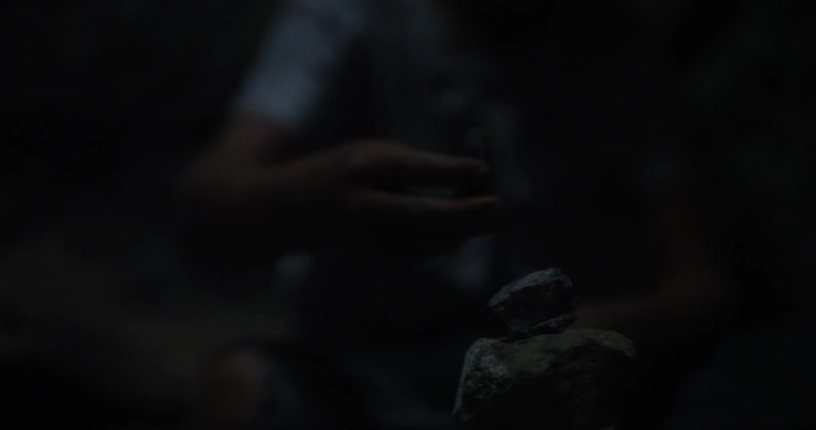 A person is stacking rocks in a dark area