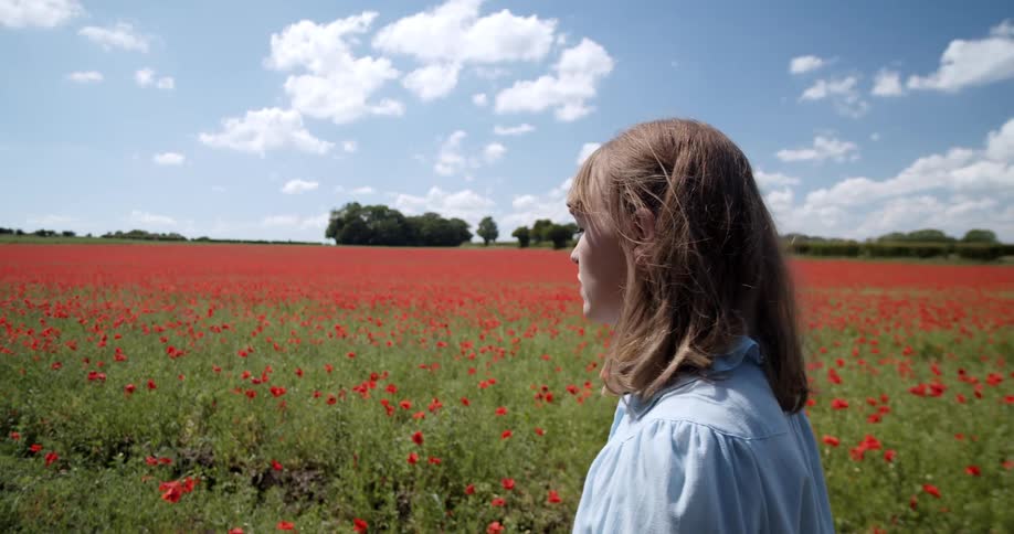 A woman is walking in a field of flowers