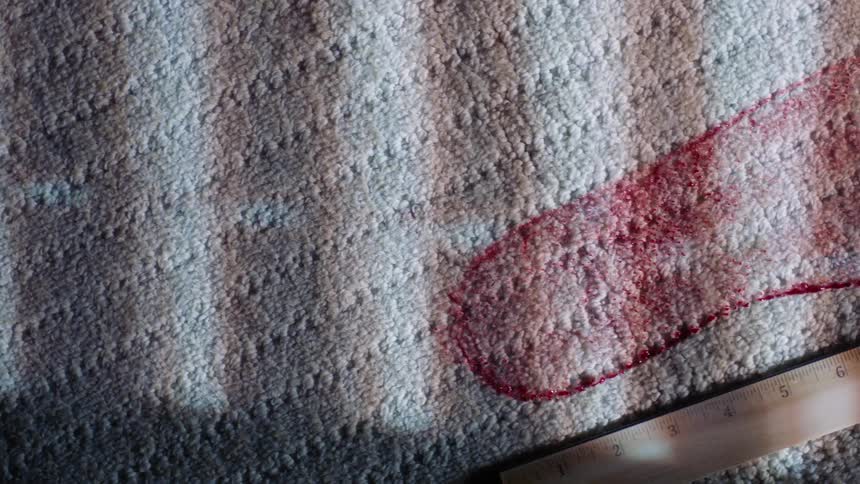Red footprint over a rug in the floor with a wooden ruler at the side