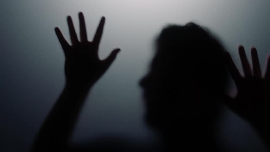 The shadow of a man who appears to be sliding down glass