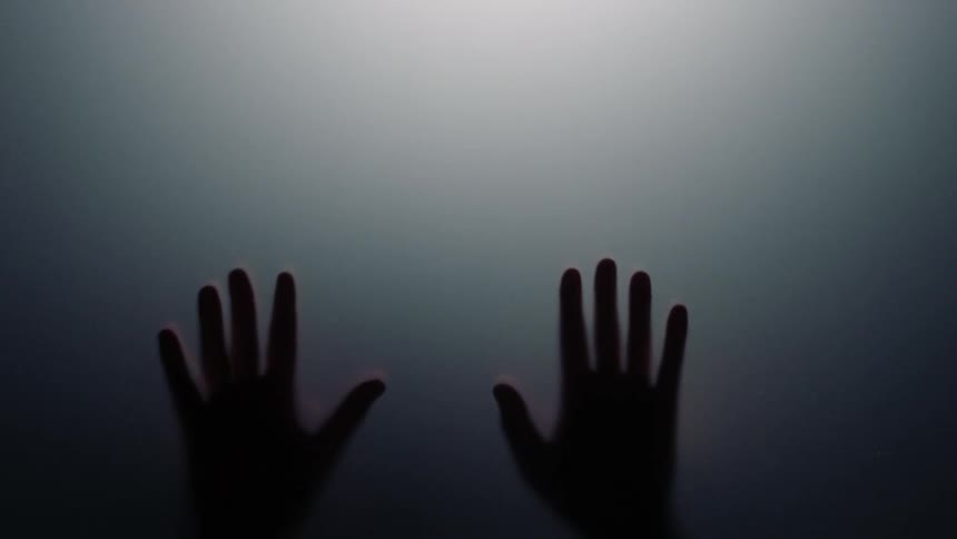 A person runs their hands down glass