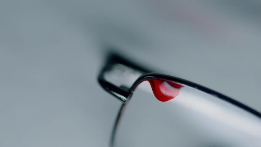 Drop of red fresh blood on the crystal of a pair of glasses
