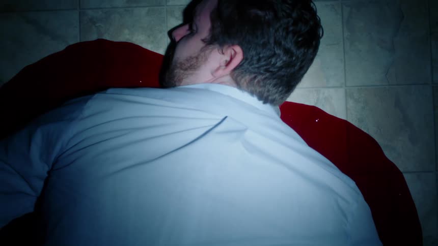 A dead man lies in a pool of red blood
