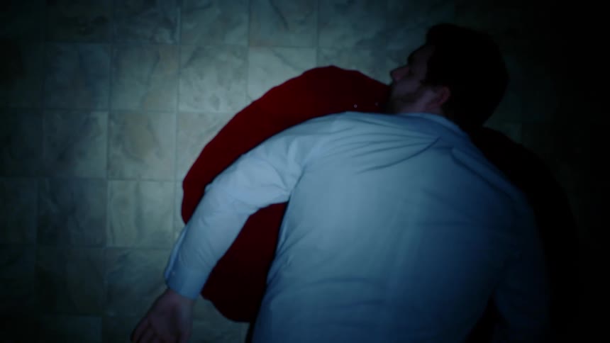 The corpse of a man lying in a puddle of blood on a tiled floor