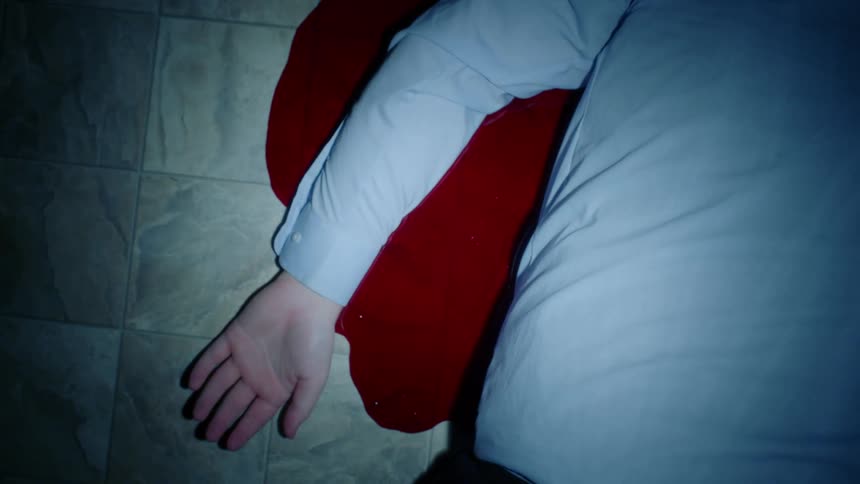 A person with a shirt laying on the floor in a puddle of blood