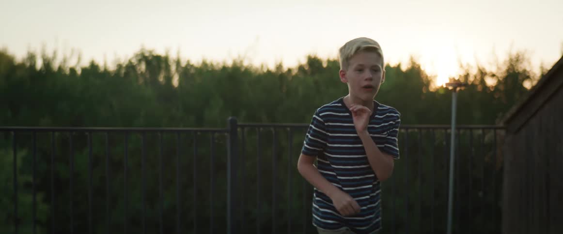 Two boys play together outside throwing a small bean bag