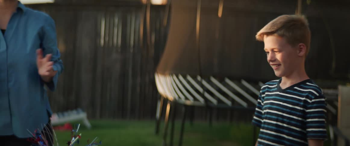 Family setting up a table decorated with american flags for a barbecue in the backyard