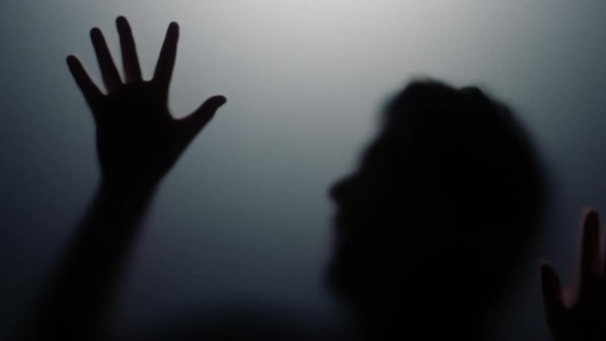 Mans silhouette can be seen through slightly milky glass slipping downward