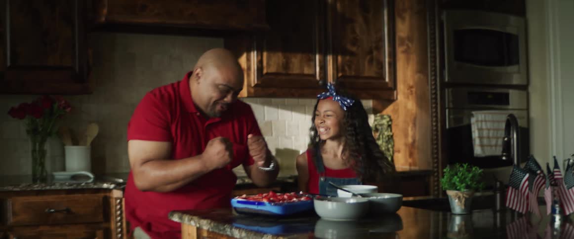 A man and a girl in a kitchen eating food