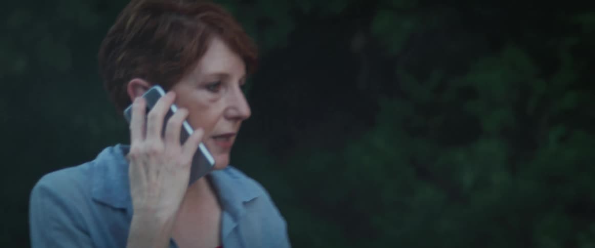 An irritated and distressed woman takes on her smartphone as she walks around her smoking vehicle on the side of the road