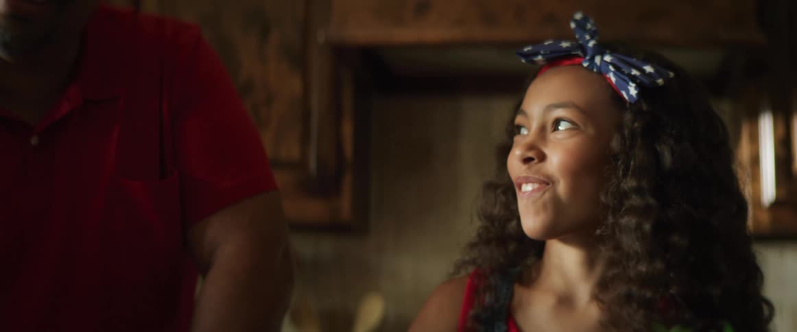 A girl tries to sneak a bite of a food but laughs when she realizes she was caught by her father