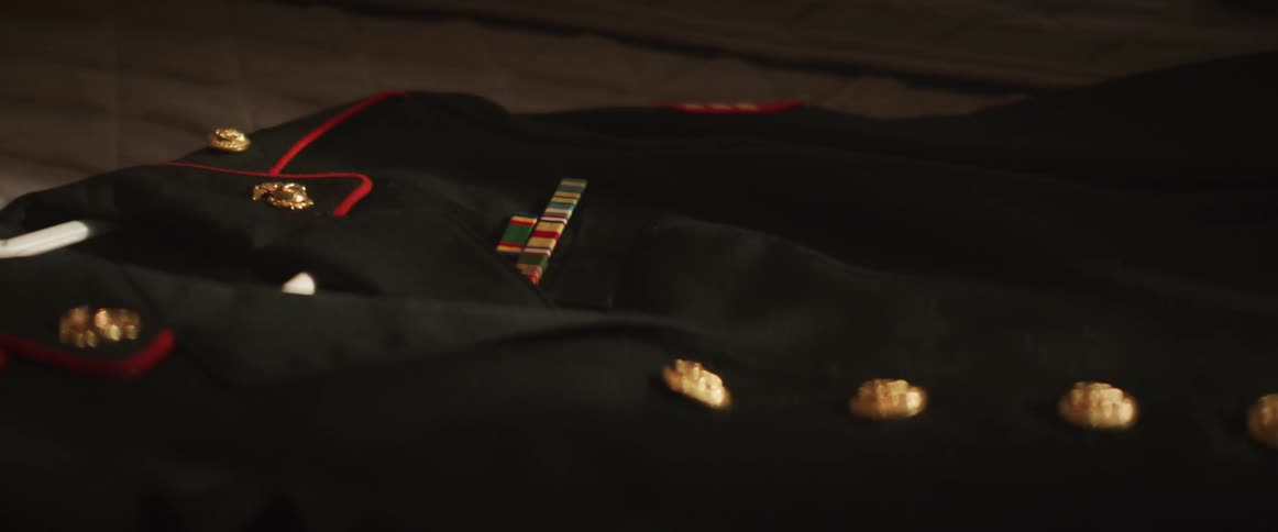 A woman's hand polishes the buttons on a military uniform