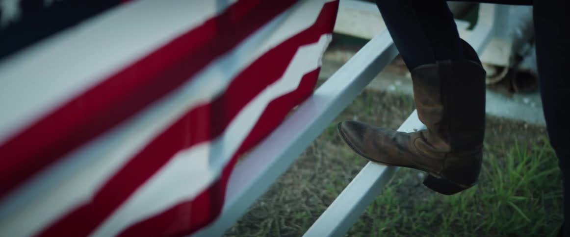 A woman puts her foot up on a railing with a flag hanging on it