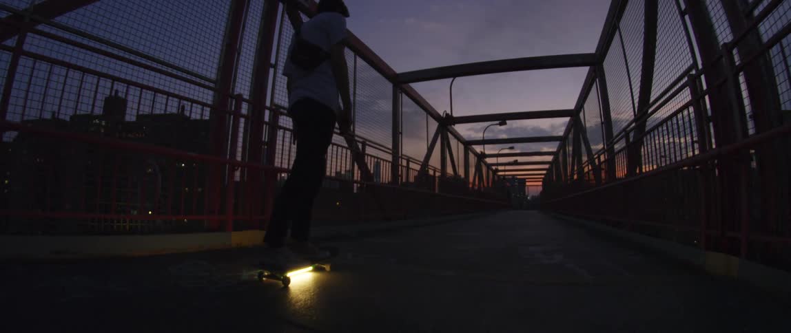 A man is skateboarding in a downtown city in the evening