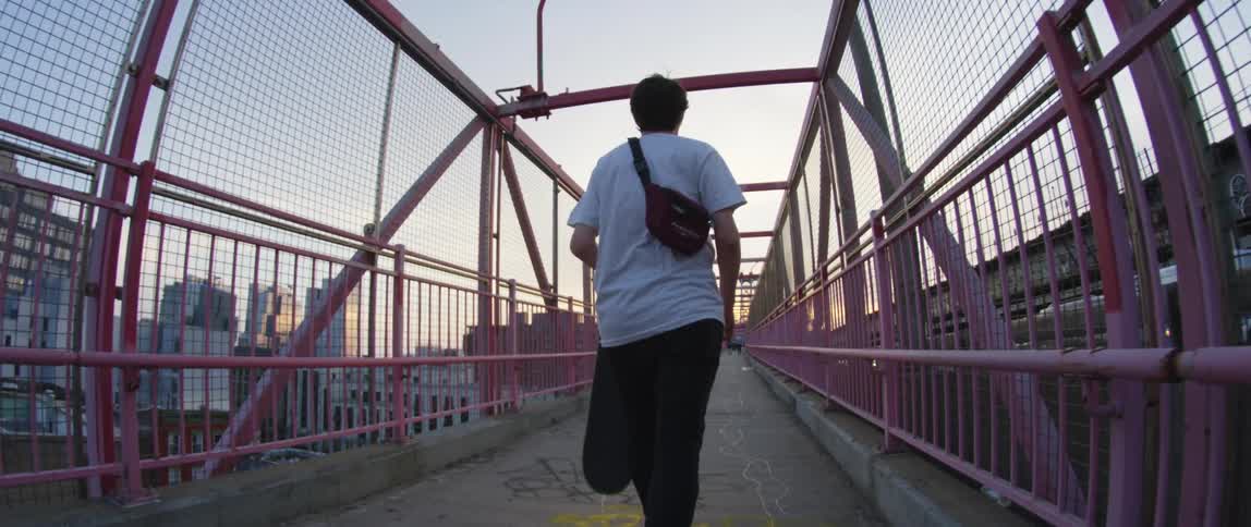 A person walks along a pedestrian bridge holding a skateboard