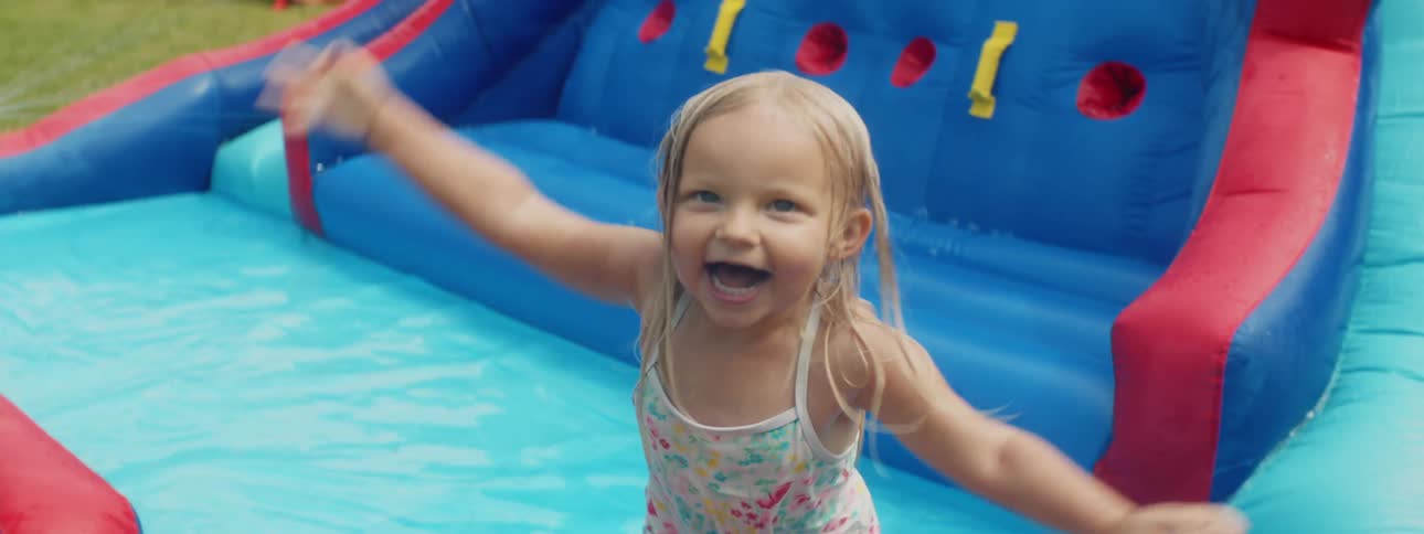 A young girl jumping up and down in the pool of an inflatable water slide