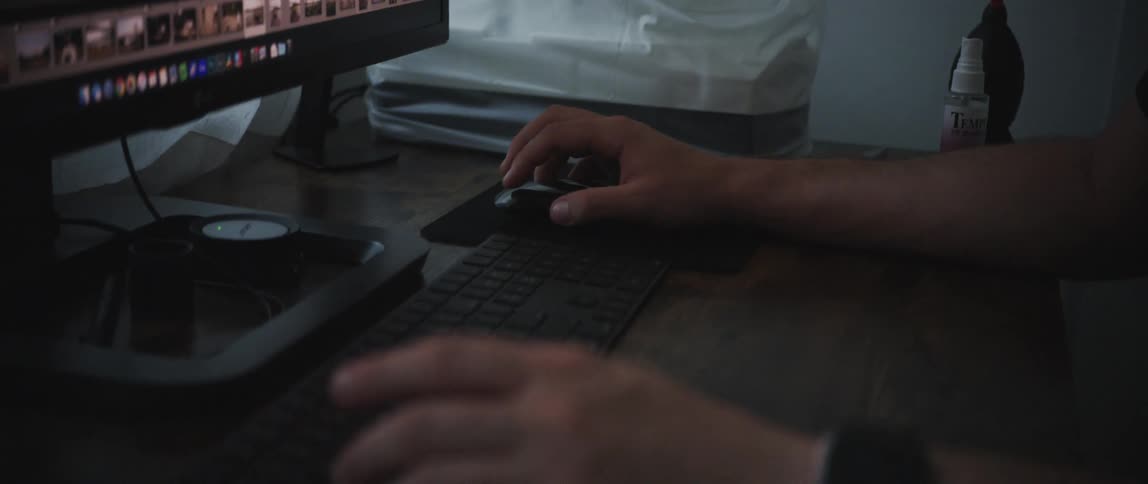 A person sits at a desk and uses software on a computer