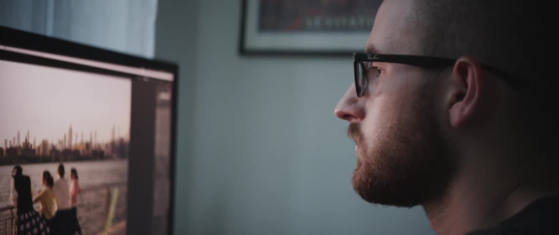 A man with glasses sitting in front of a computer screen