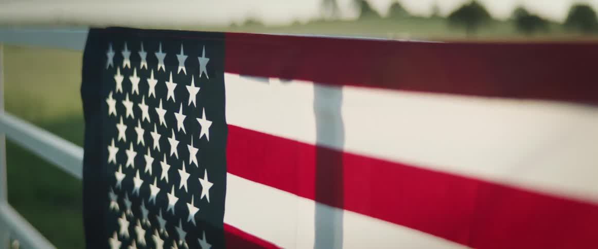 Wind blowing through an american flag hanging on a fence