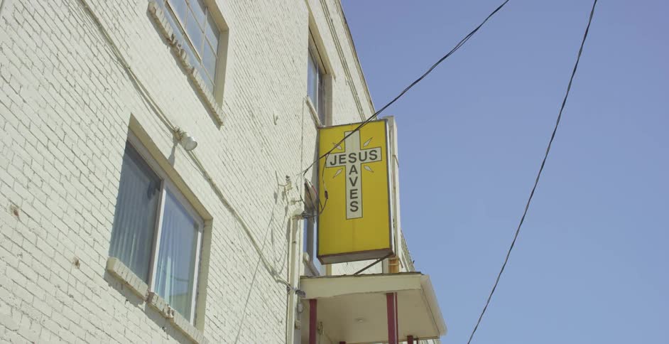 A religious sign on the side of a brick building