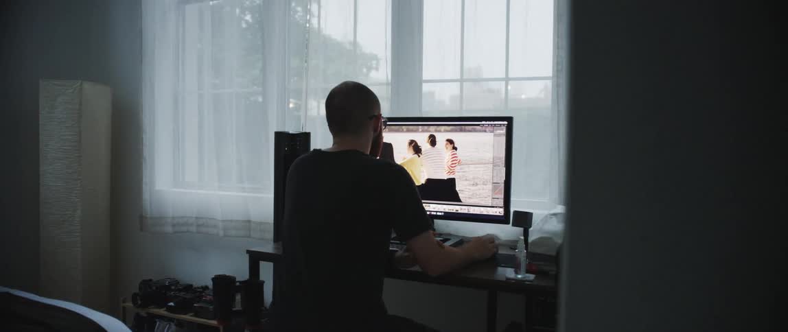 A man is sitting at a desk and browsing on a computer