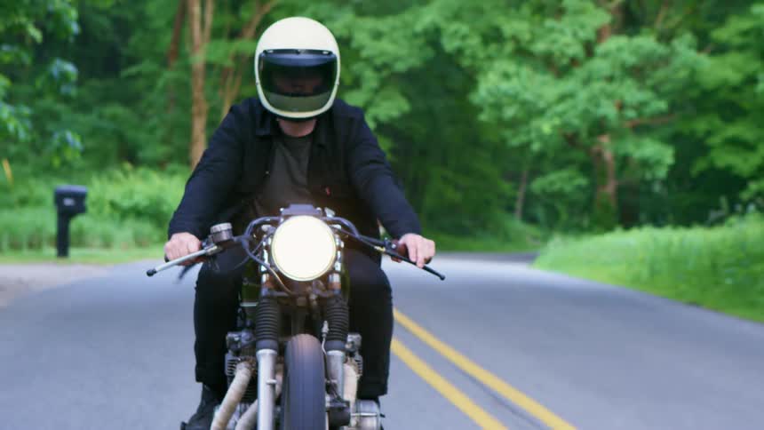 A man is riding a motorcycle down a road