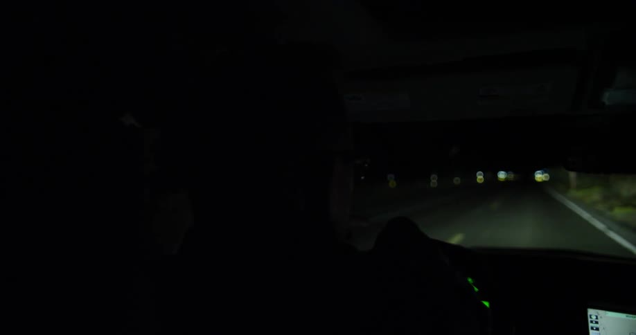 A vehicle is traveling down a road at night