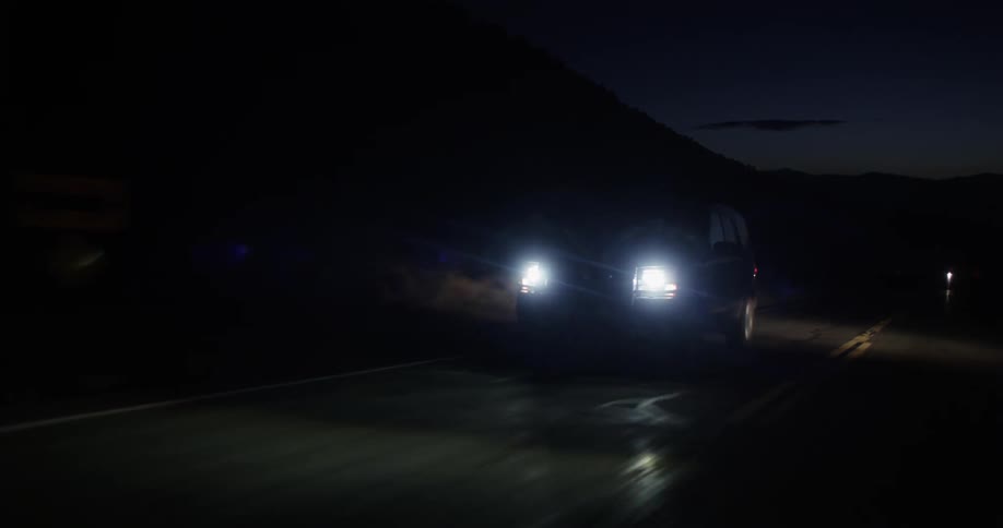 A vehicle is traveling down a road at night