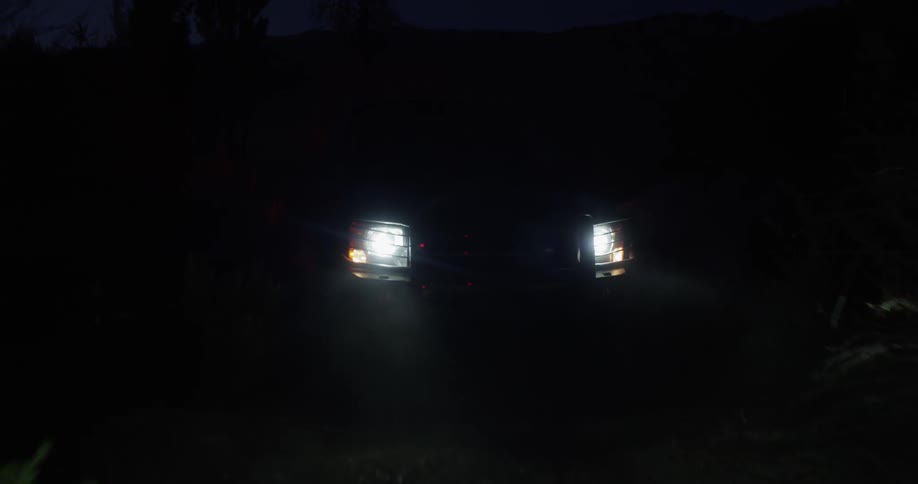 A vehicle drives off road in the wilderness at night