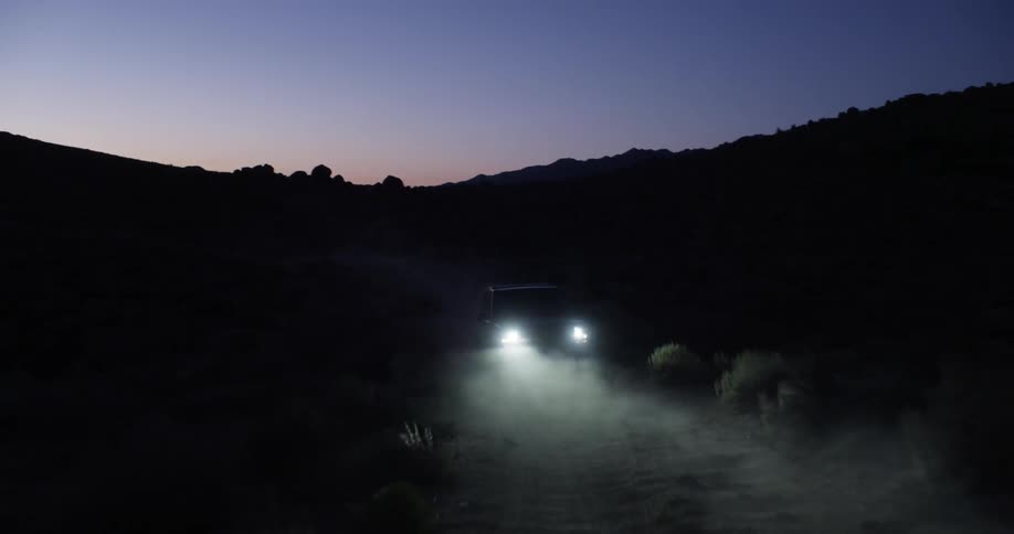 A vehicle drives in the wilderness at dusk