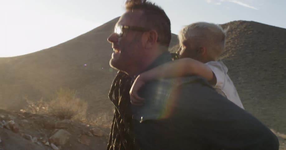 A boy is piggybacking on a man's shoulder on a sunny day