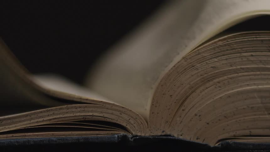 A book with wind turning the pages with a black background