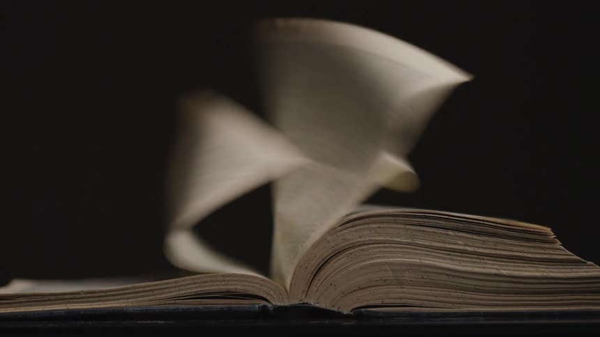 A book with the pages turning in the wind with a dark gray background