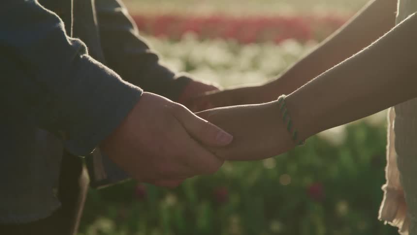 A husband and wife are holding hands outdoors