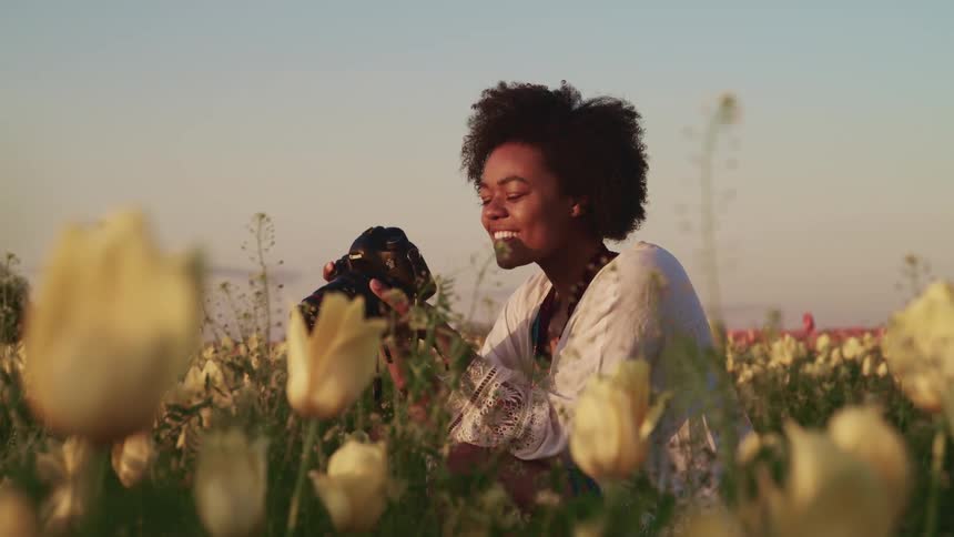 A woman in a field of flowers takes pictures