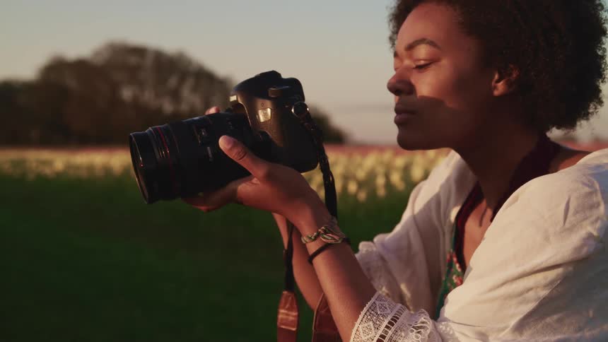 A female photographer takes a photo and stares at the image