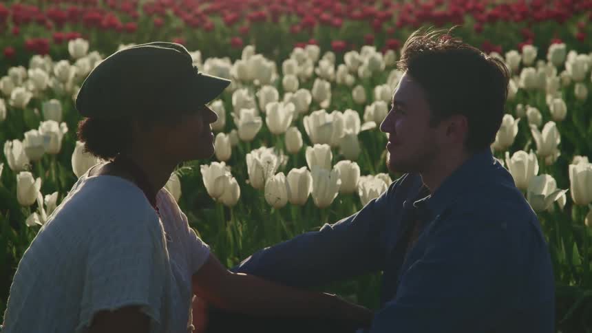 A couple sit in the tulips together