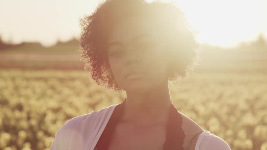 A woman is standing in the field of flowers at sunrise